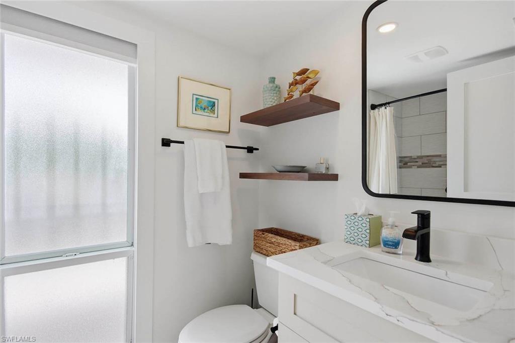 Primary bathroom featuring a white vanity with an integrated rectangular sink, light stone countertop, and matte black wall-mounted faucet