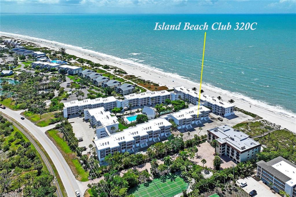 Island Beach Club 320C showcases a modern oceanfront complex with multi-level residential architecture, expansive hardscaped courtyard with mature landscaping, resort-style amenities including a resort pool and spa facilities, direct beachfront access, and lush tropical grounds with established vegetation throughout the property