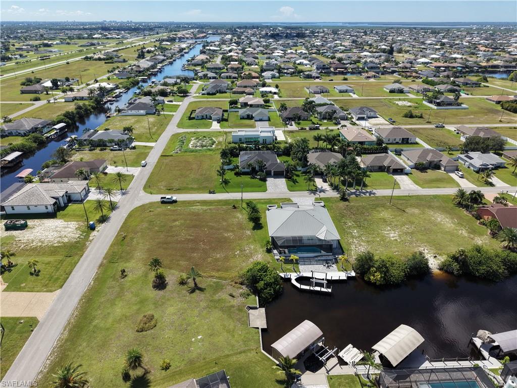 Waterfront estate lot featuring expansive manicured grounds with mature landscaping, direct canal access with boat dock and covered boat lifts, and panoramic vistas across the waterway