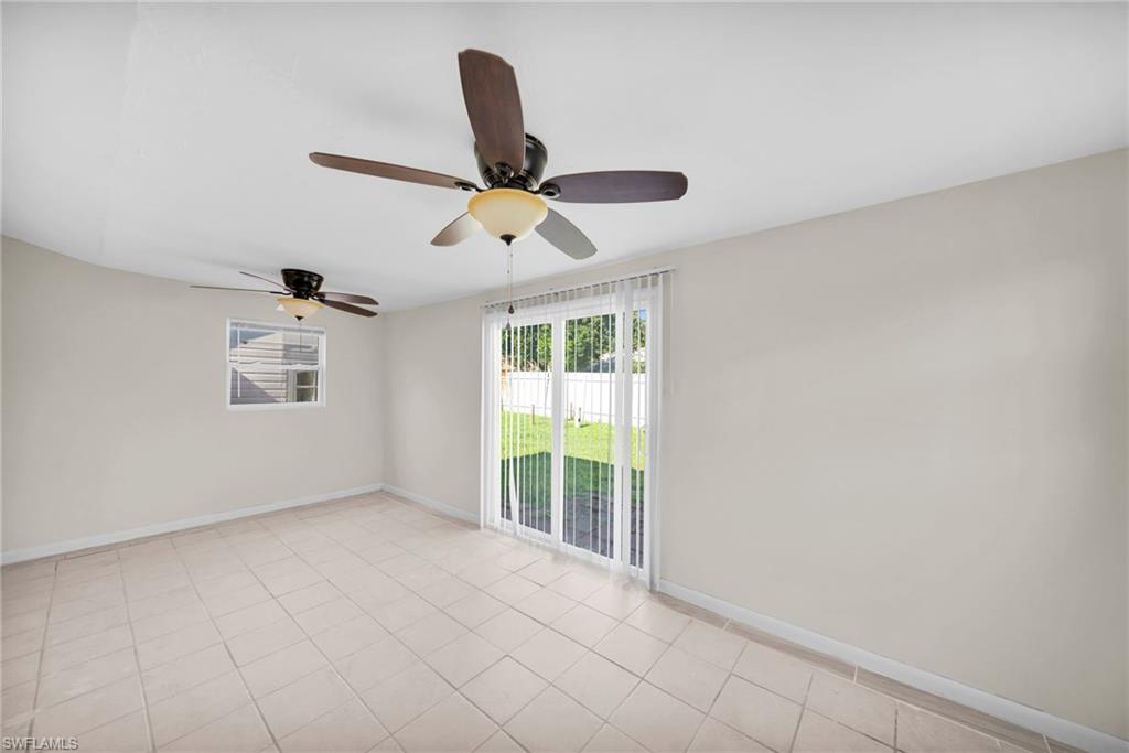 Bright, open room featuring tile flooring, a ceiling fan with integrated lighting, a window air conditioning unit, and French doors providing natural light and access to the exterior