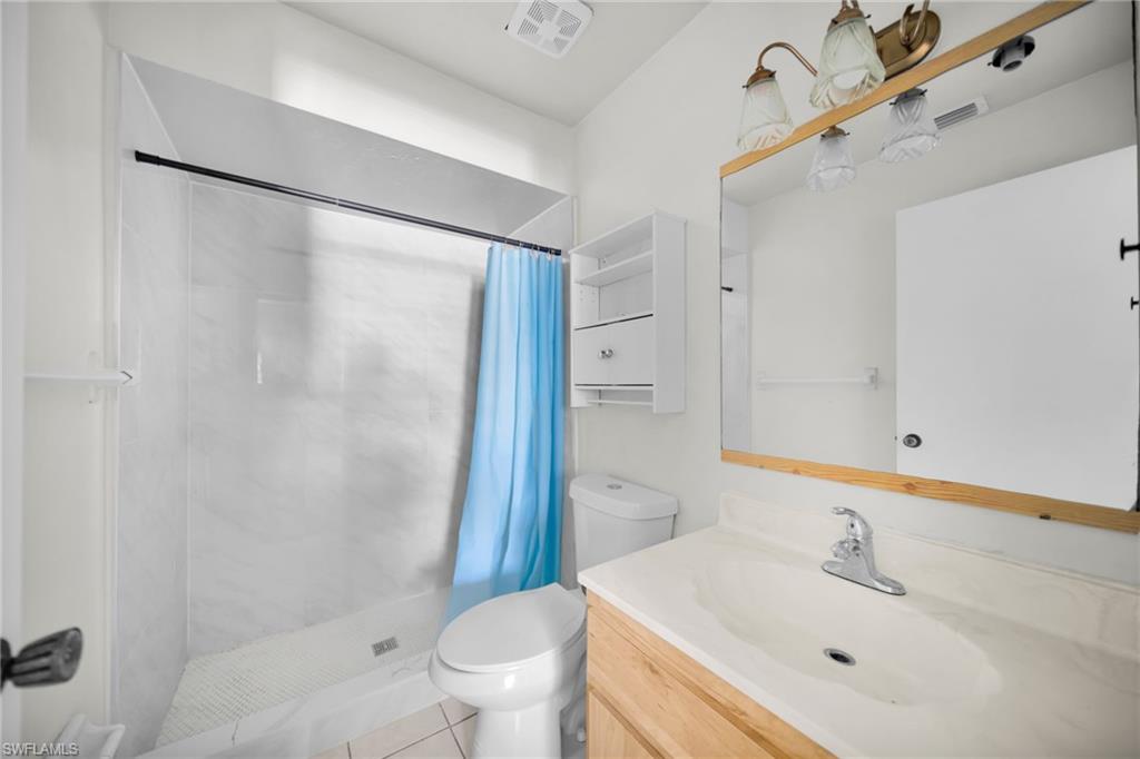 Modern bathroom featuring a walk-in shower with glass enclosure and blue curtain rod, white subway tile surround, and integrated shelving