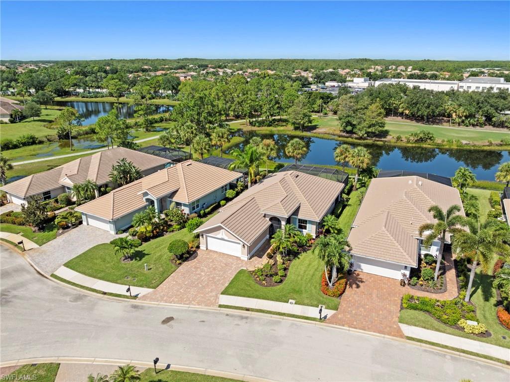 Aerial view showcasing two single-story homes with barrel tile roofing situated on manicured lots featuring mature palms and lush landscaping