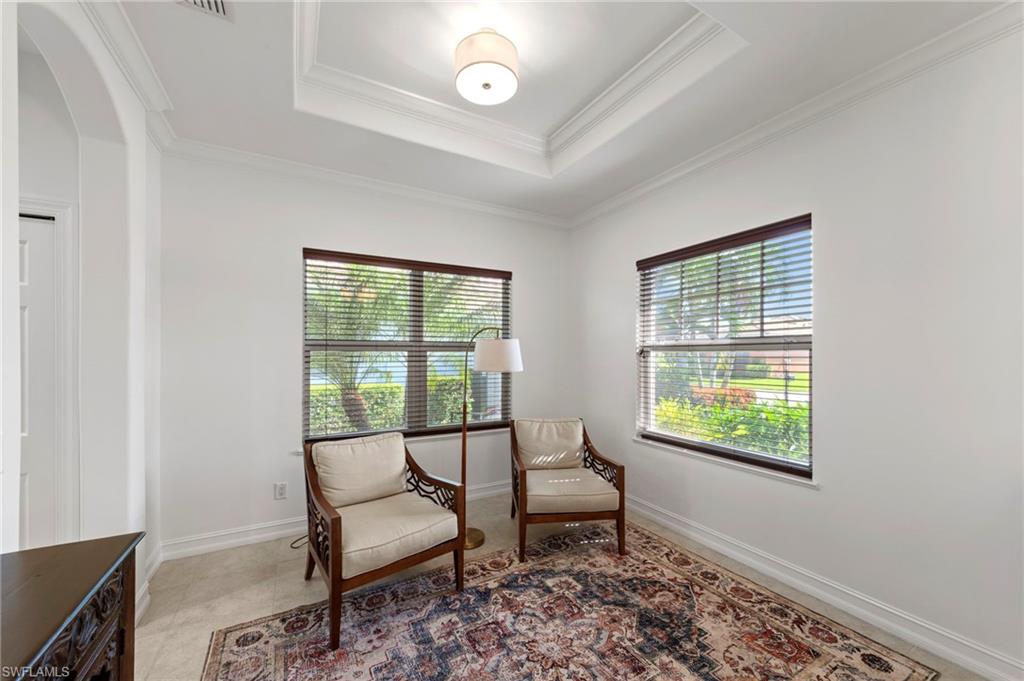 Bright and airy sitting room featuring dual large windows with operable blinds, coffered ceiling with recessed lighting, wood-finish flooring, and a decorative area rug