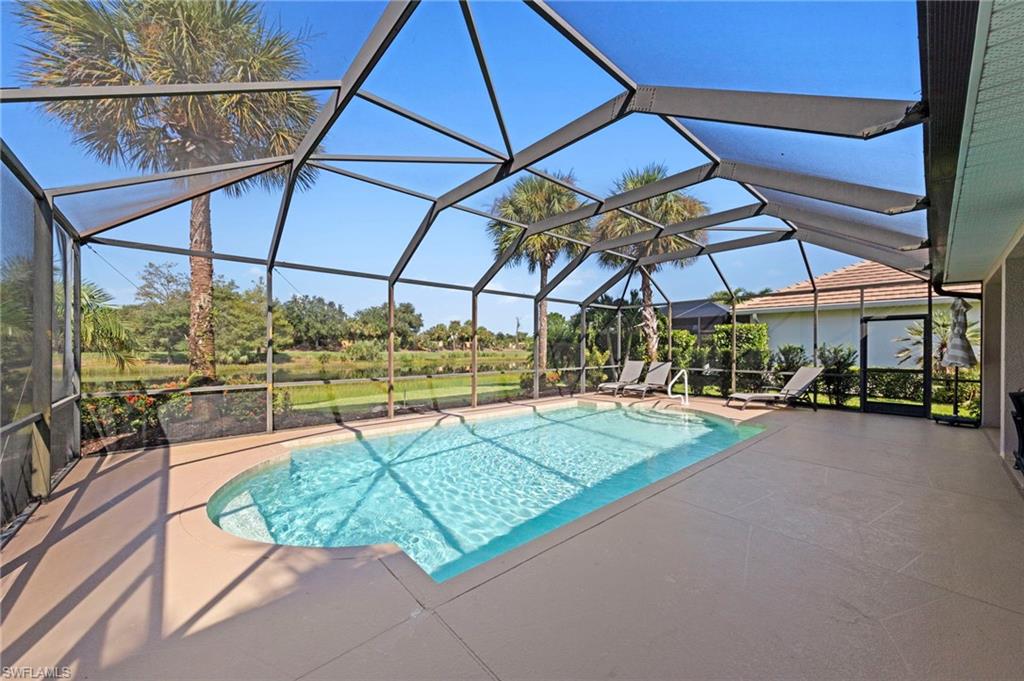 Screened lanai with soaring peaked glass ceiling and aluminum framing, featuring a resort-style swimming pool with turquoise finish and concrete decking