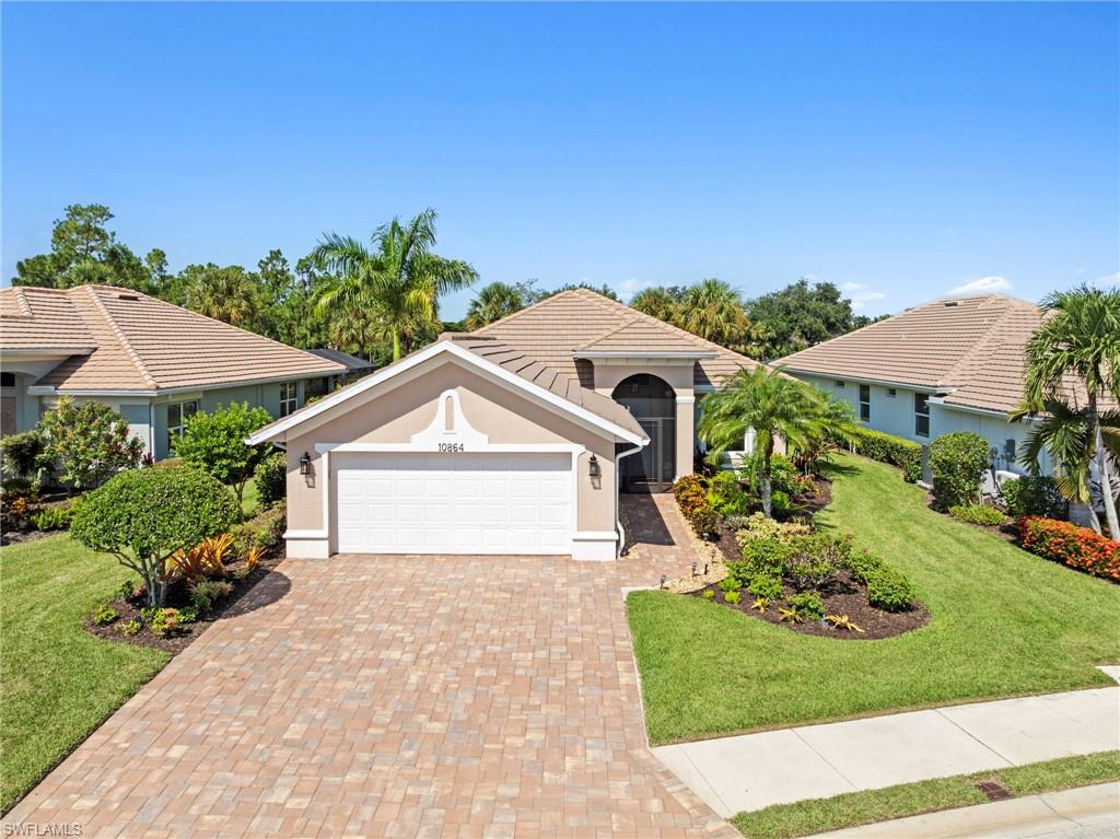 Elegant single-story residence featuring a barrel tile roof, white two-car garage with arched detailing, and a circular driveway with clay brick pavers