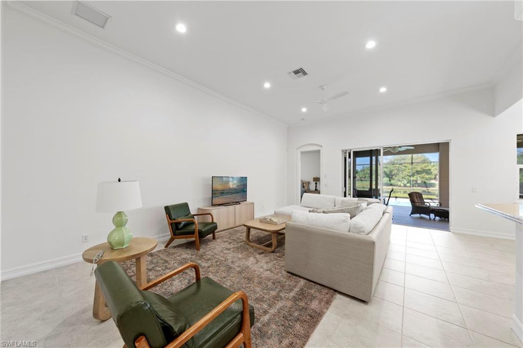 Bright, open-concept living area featuring recessed ceiling lighting, light wood-finish flooring throughout, and expansive glass sliding doors opening to outdoor space