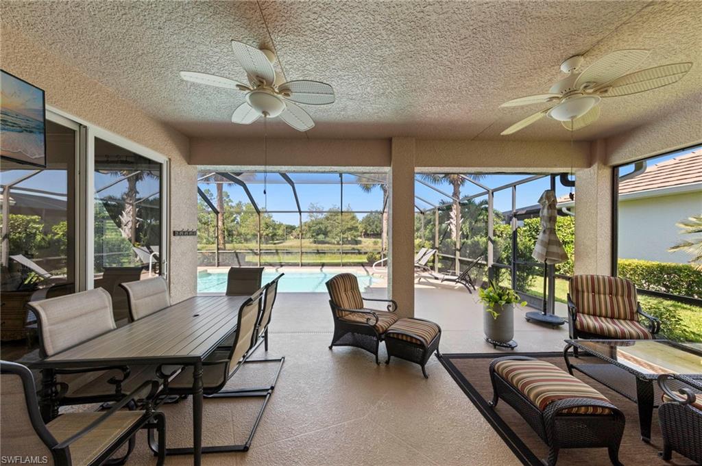 Expansive screened lanai with multiple ceiling fans, extensive sliding glass doors, and direct pool access