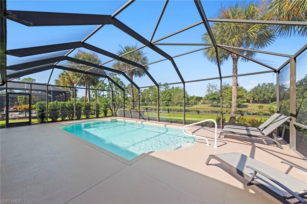 Screened-in pool enclosure featuring a rectangular swimming pool, integrated steps, and a white handrail