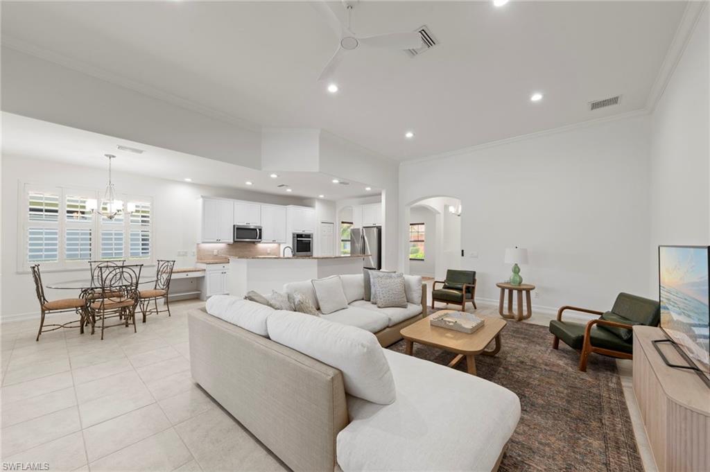 Open-concept living space with tile flooring, white walls, recessed lighting, and crown molding
