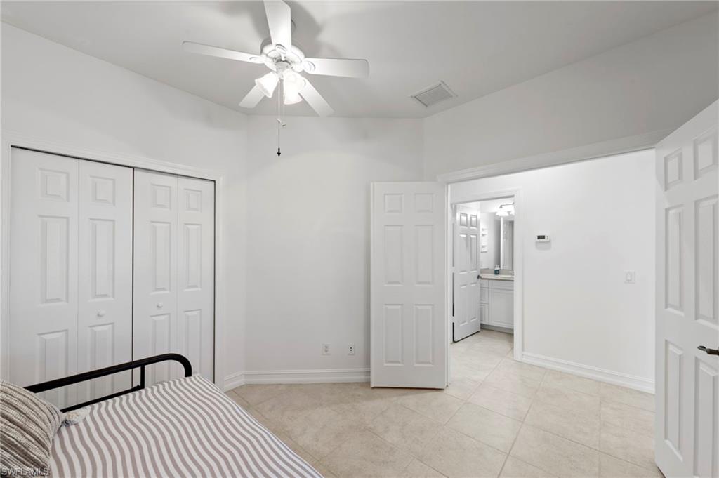 Neutral tone tile flooring, white walls, white ceiling fan, white bi-fold closet doors, and recessed lighting