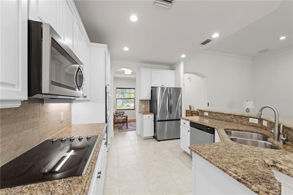 Kitchen featuring white cabinetry, granite countertops, stainless steel appliances, a double basin sink, and tile flooring