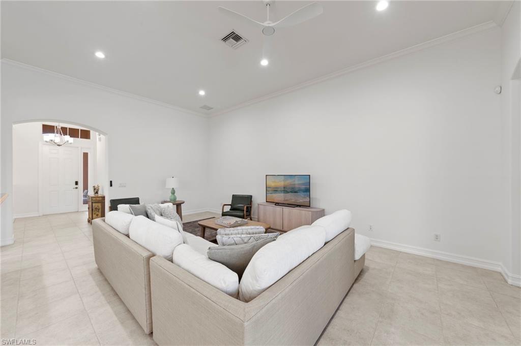 Spacious living area featuring a sectional seating arrangement, recessed ceiling lighting, and tile flooring throughout