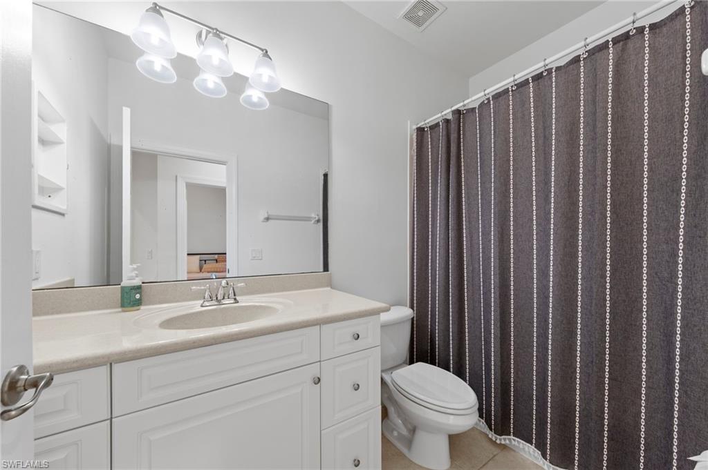 White vanity with a single basin sink, light-toned countertop, and an expansive wall-mounted mirror