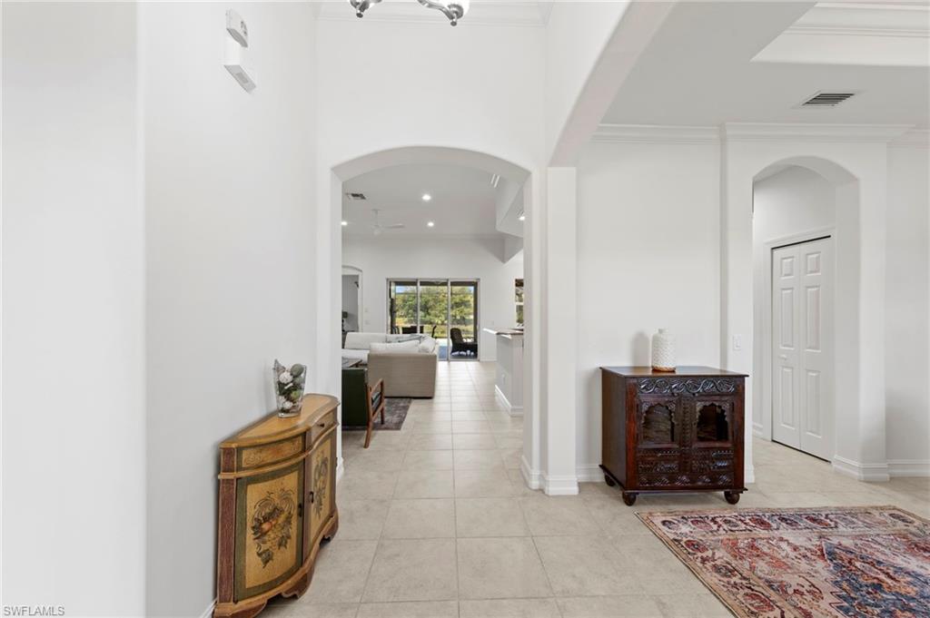 Arched doorways, tile flooring, recessed lighting, and crown molding