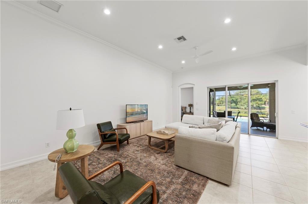 Bright, open living space featuring recessed ceiling lighting, light wood-finish flooring throughout, and a spacious cream upholstered sectional