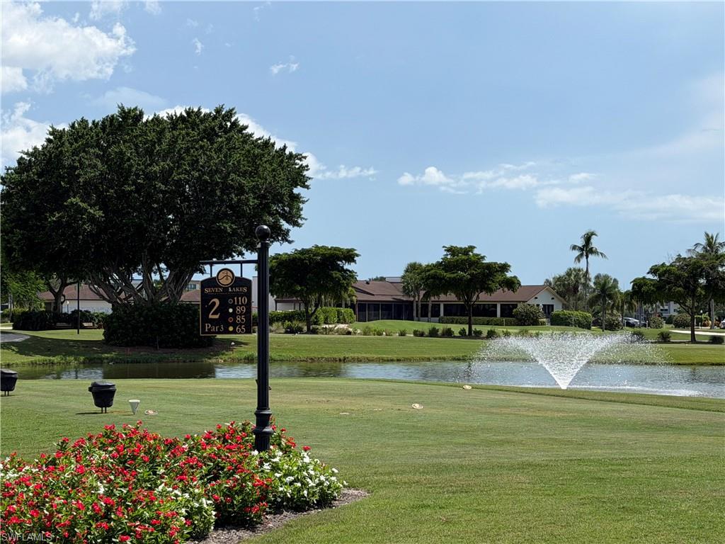 Manicured golf course featuring lush green turf, a decorative fountain, and mature tropical landscaping