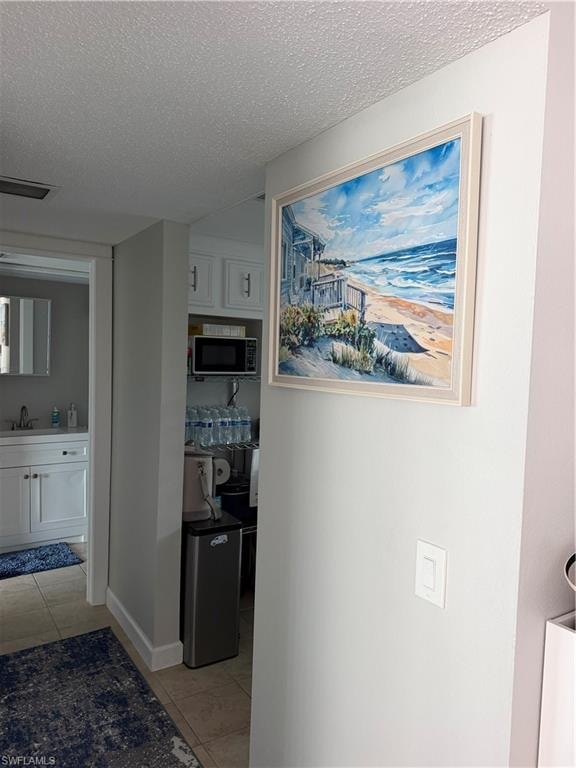 Tile flooring, white shaker cabinetry, stainless steel microwave, and built-in shelving
