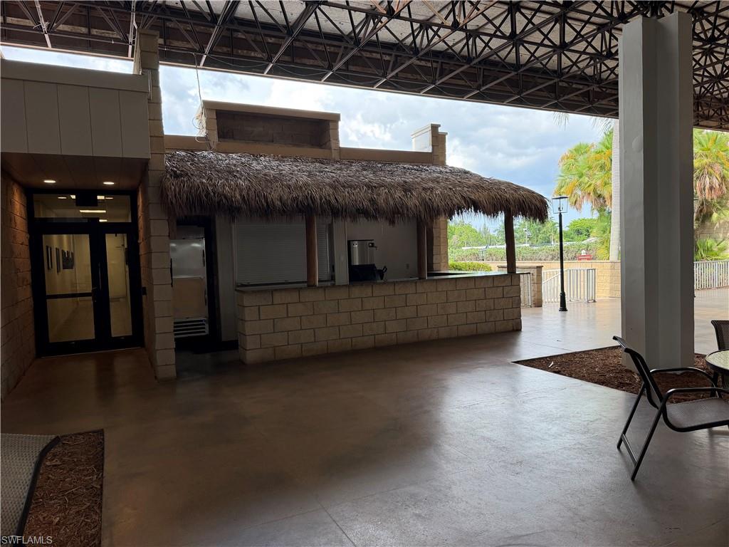 Covered outdoor patio with a built-in bar, thatched roof, and concrete flooring