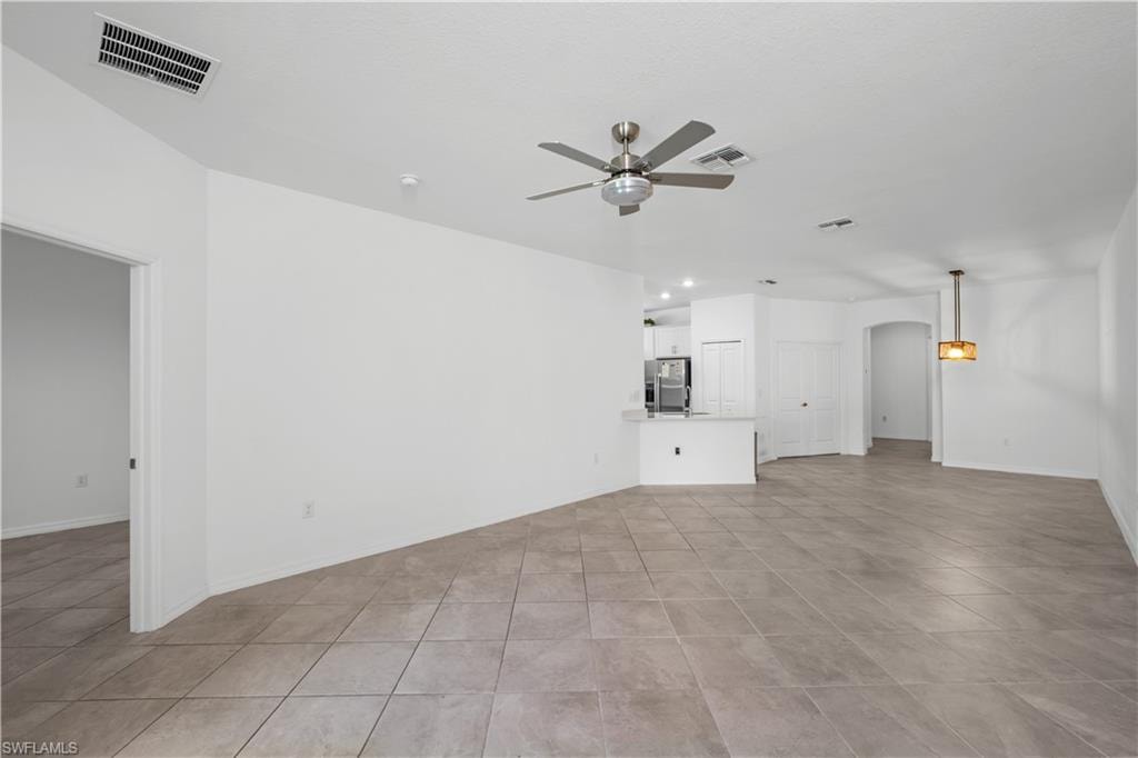 Spacious living area featuring tile flooring, a ceiling fan, and a contemporary pendant light fixture