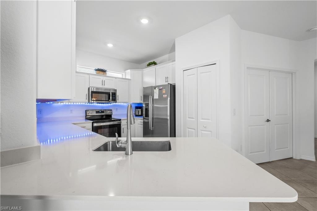 Kitchen featuring white shaker cabinetry, stainless steel appliances, white countertops, and a stainless steel sink with a high-arc faucet