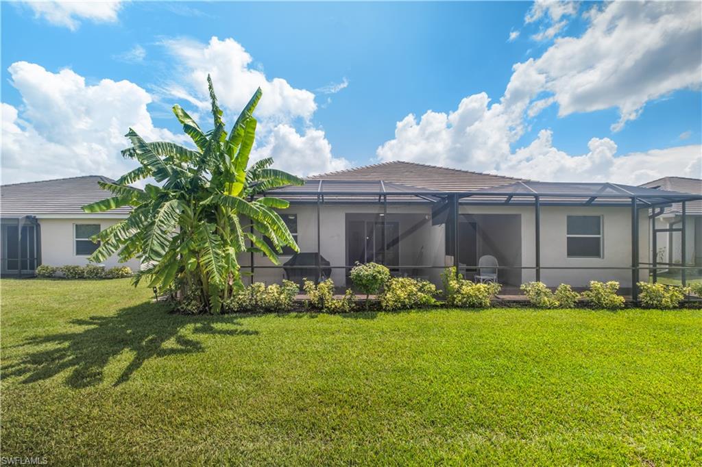 Expansive backyard with a manicured lawn, established plantings, and a screened-in patio