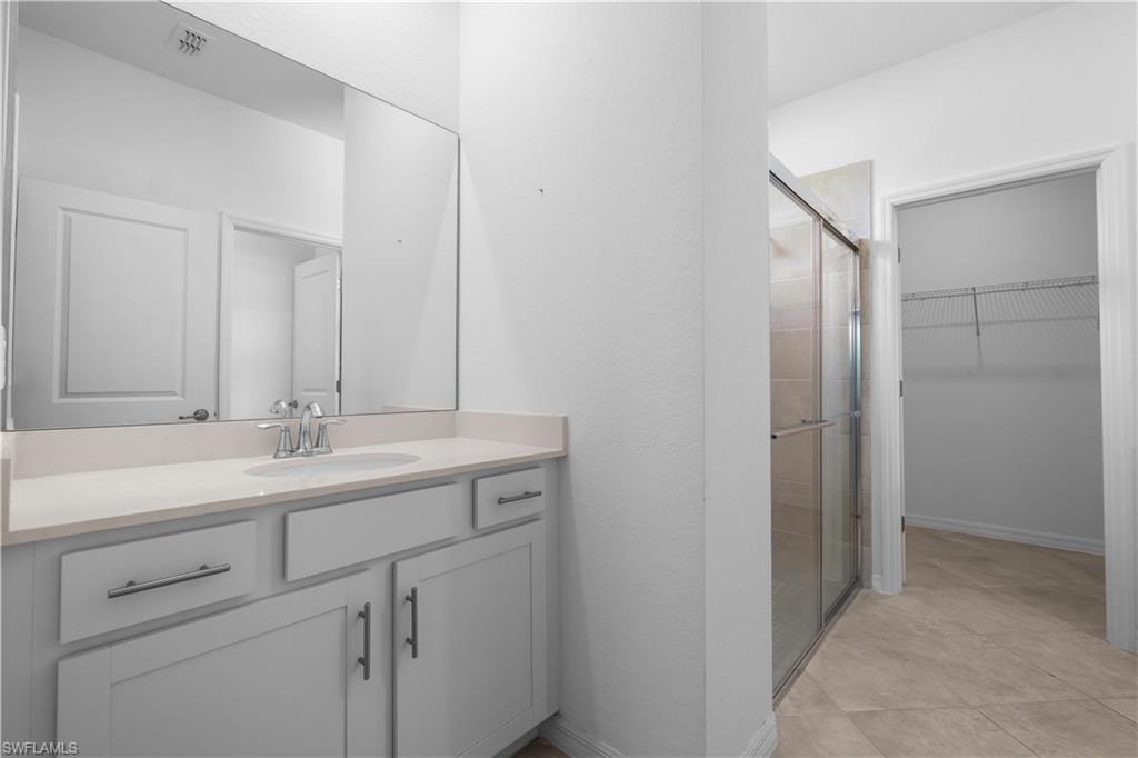 Master Bathroom Continuationfeaturing a dual vanity with light-toned countertop, a frameless mirror, and a glass-enclosed shower