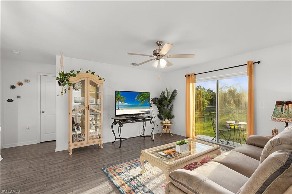 Sliding glass door leading to exterior, wood-finish flooring, ceiling fan with integrated lighting, white walls, and a built-in display cabinet