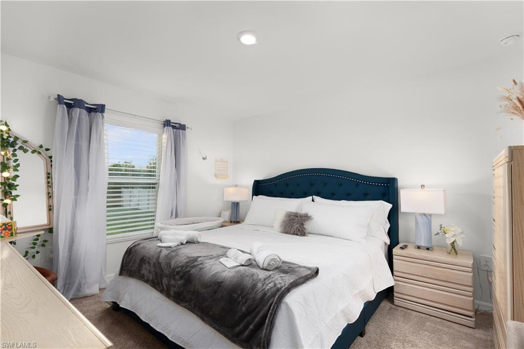 Recessed ceiling lighting illuminates a room with light-toned walls and carpet