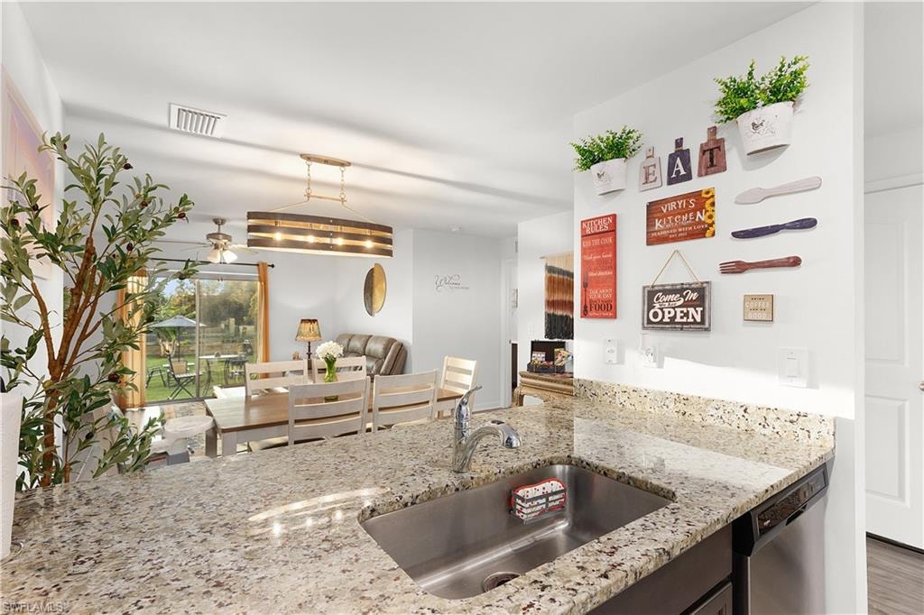 Granite-style countertop with an undermount stainless steel sink, wood-finish flooring, and a sliding glass door leading to the exterior