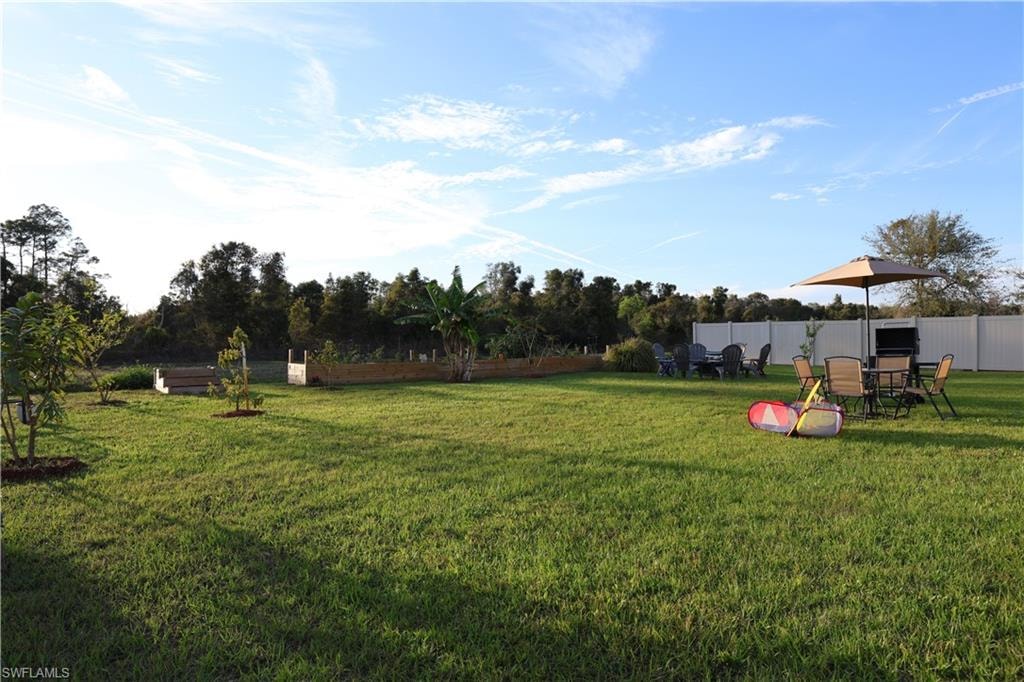 Expansive green lawn with a white privacy fence and established trees