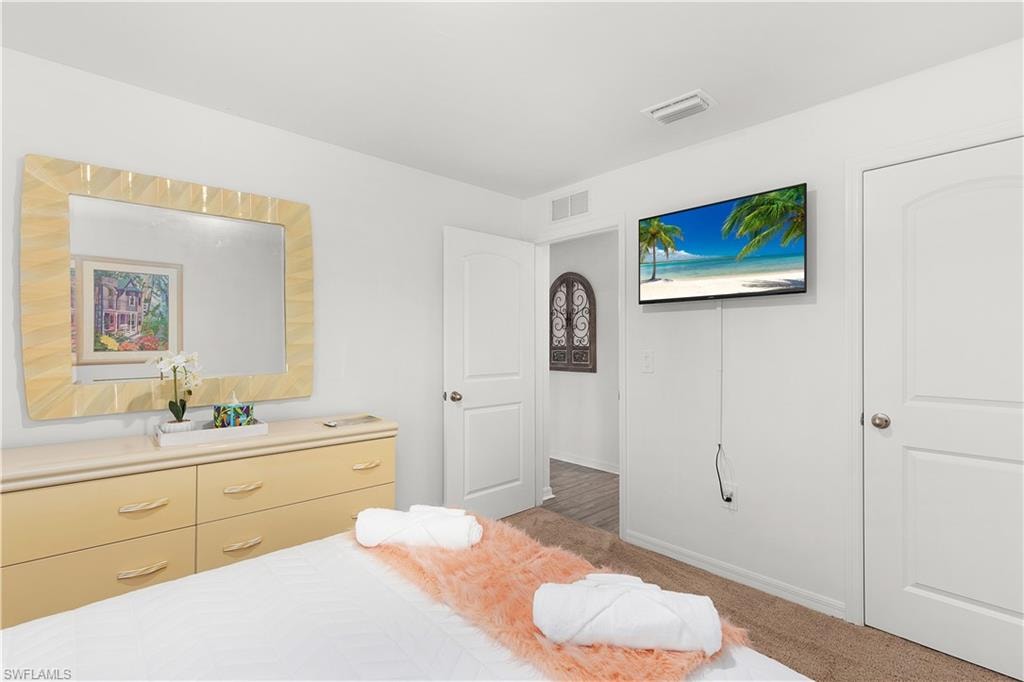 White painted walls, mounted television, light-toned dresser, framed mirror, and interior doors