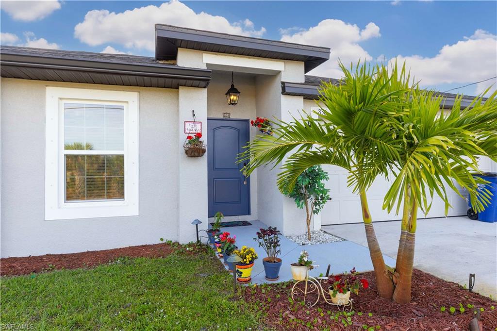 Stucco exterior with a contrasting dark blue entry door, an exterior wall light fixture, and a single window with white trim