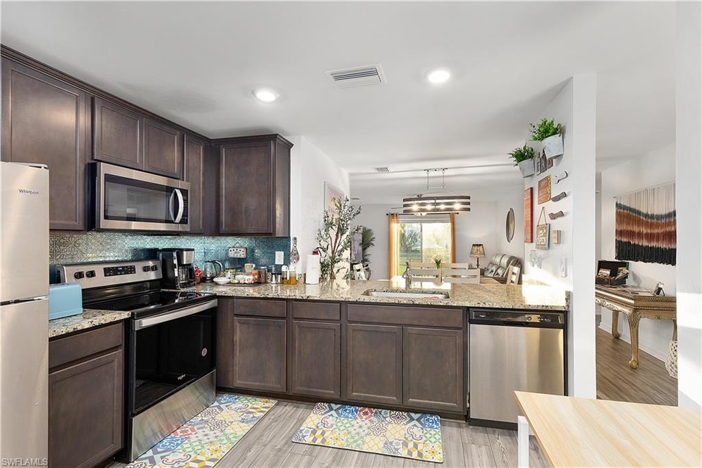 Dark wood-finish cabinetry with stainless steel appliances, granite countertops, and a tile backsplash