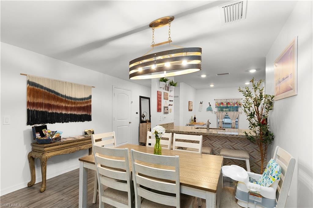 Open concept dining area featuring wood-finish flooring, a contemporary chandelier, and recessed lighting