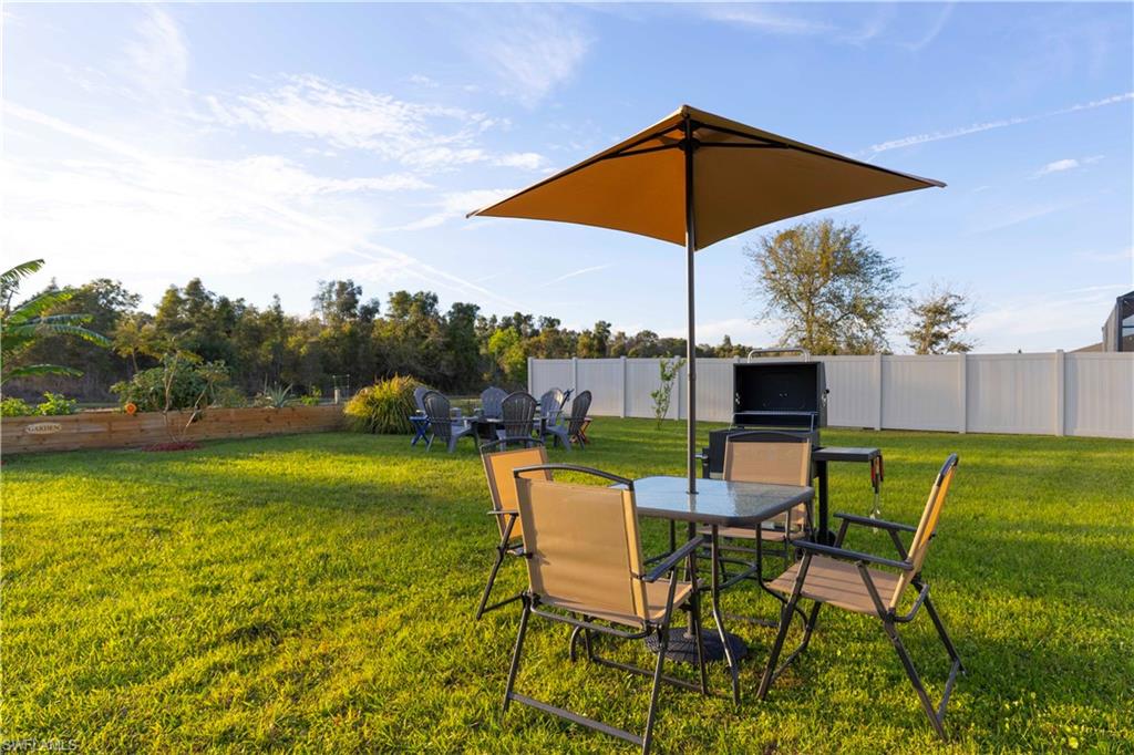 Expansive backyard featuring a manicured lawn, a privacy fence, and a raised garden bed