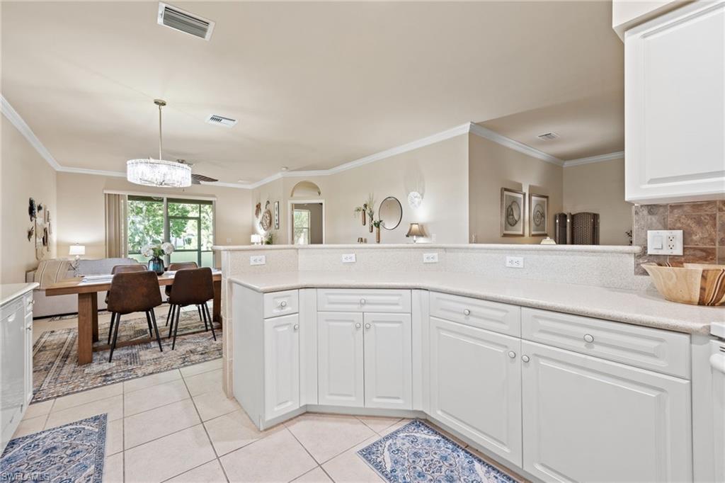 Sophisticated kitchen featuring white cabinetry with ample storage, tile flooring, stainless steel appliances, and a curved island with multiple prep zones
