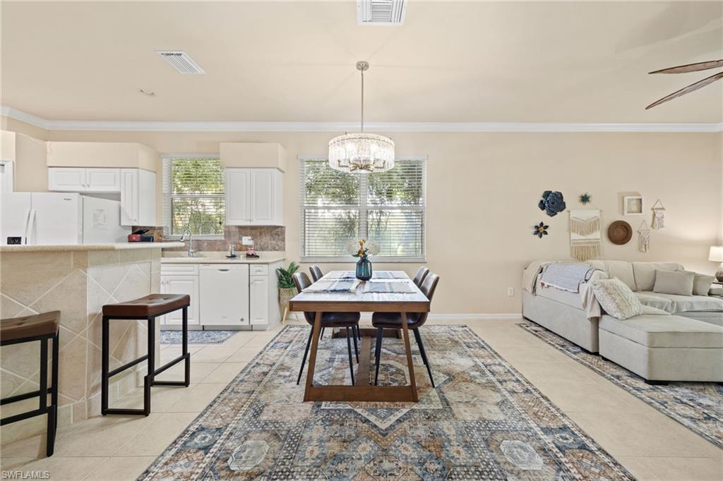 Open-concept living and dining area featuring light wood-finish flooring, geometric patterned area rug, and a wood dining table with seating for six