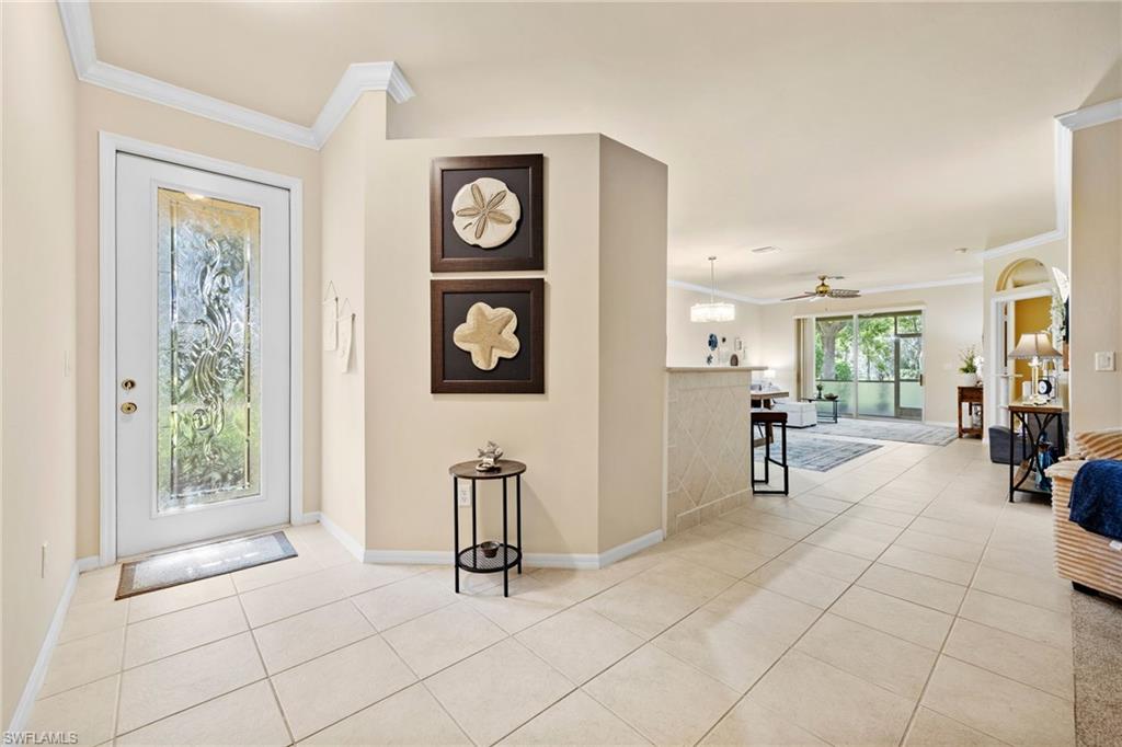 Bright foyer with ceramic tile flooring, recessed ceiling detail, and glass-paneled entry door with sidelights
