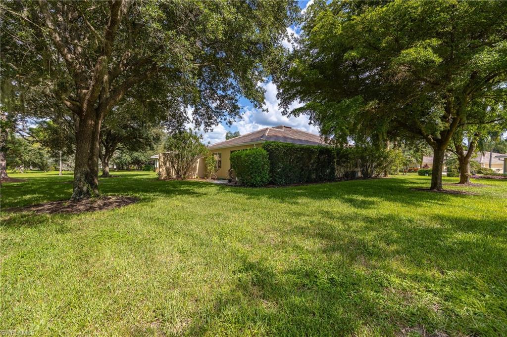 Expansive grounds anchored by mature shade trees and lush lawn, with a brick residence featuring a distinctive domed roof structure positioned as the focal point of this generous lot
