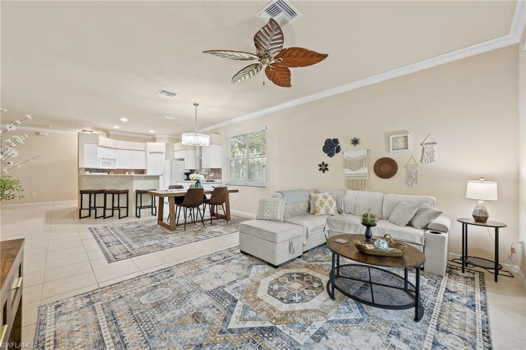 Open-concept living area with tile flooring and crown molding