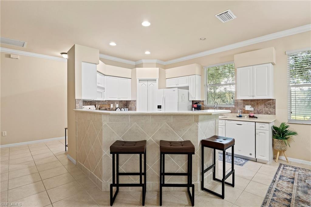 Bright kitchen featuring white cabinetry, tile flooring, and a central island with seating