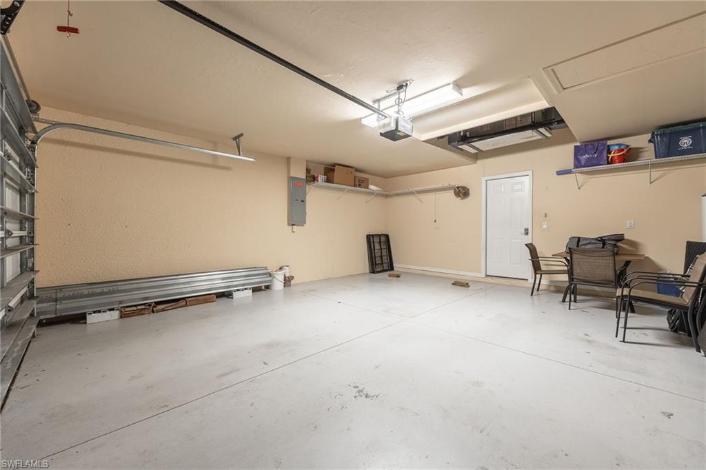 Spacious garage with epoxy-coated concrete flooring, overhead storage shelving, fluorescent ceiling lighting, and ample square footage for vehicle parking and additional storage needs