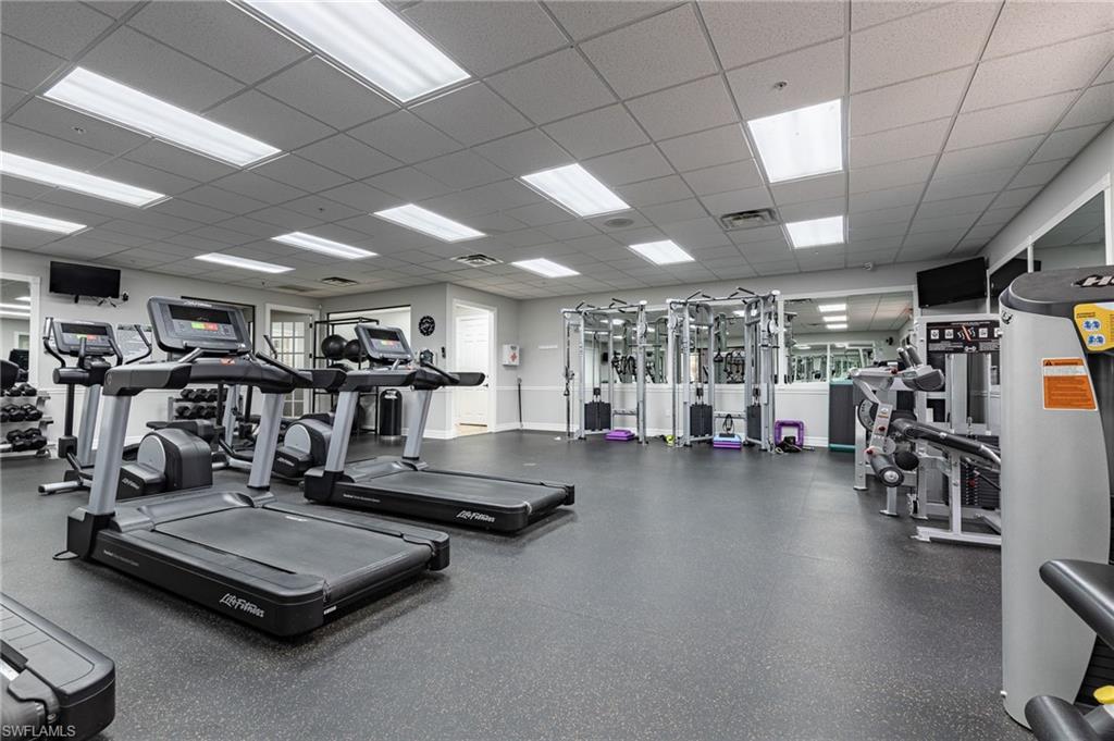 Fitness area with resilient flooring, multiple treadmills, strength training equipment, and reflective wall panels