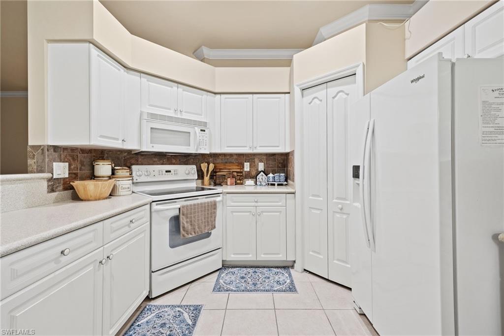White cabinetry with silver-tone hardware, white appliances, and a tiled backsplash
