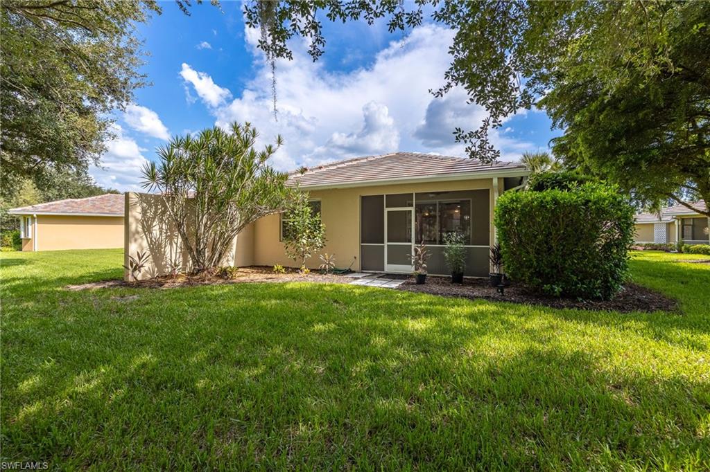 Charming single-story residence showcasing a sprawling manicured lawn, mature landscaping with native palmettos and established trees, and a covered rear porch