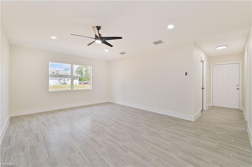 Bright, open room featuring wood-finish flooring throughout, recessed ceiling lighting, and a contemporary ceiling fan
