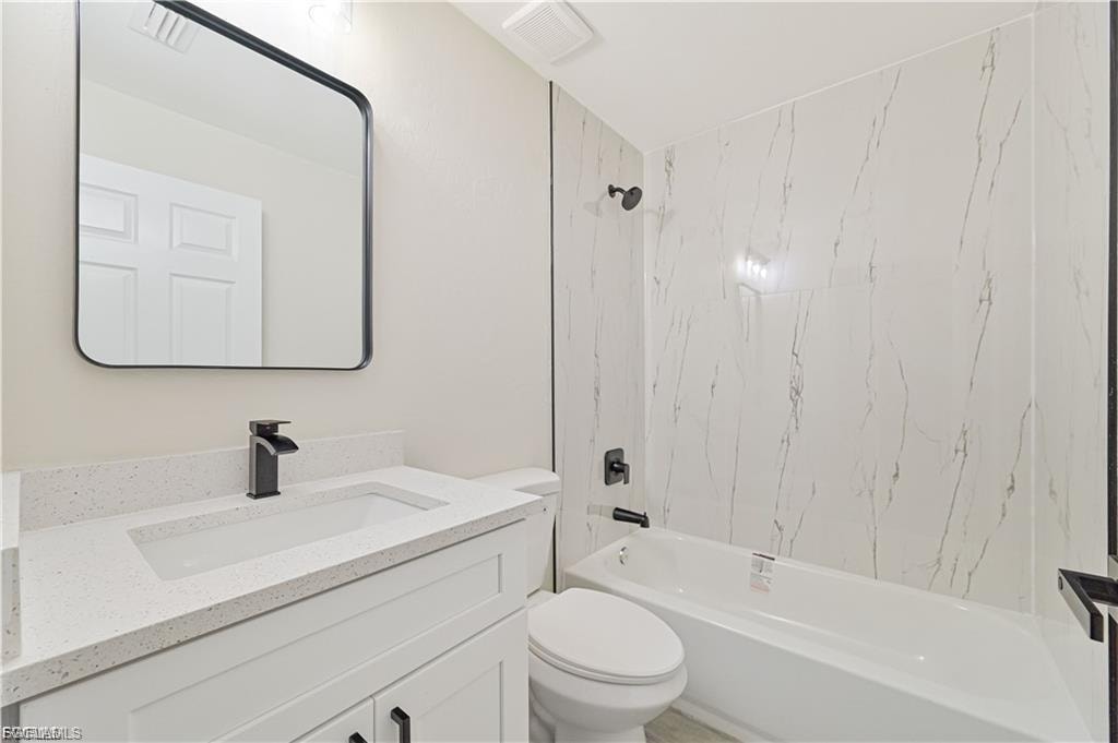 White vanity with integrated sink, speckled countertop, and matte black faucet
