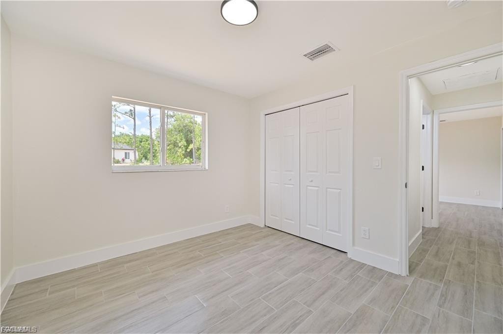 Neutral-toned room featuring a window, light-colored walls, white bi-fold closet doors, and wood-finish flooring
