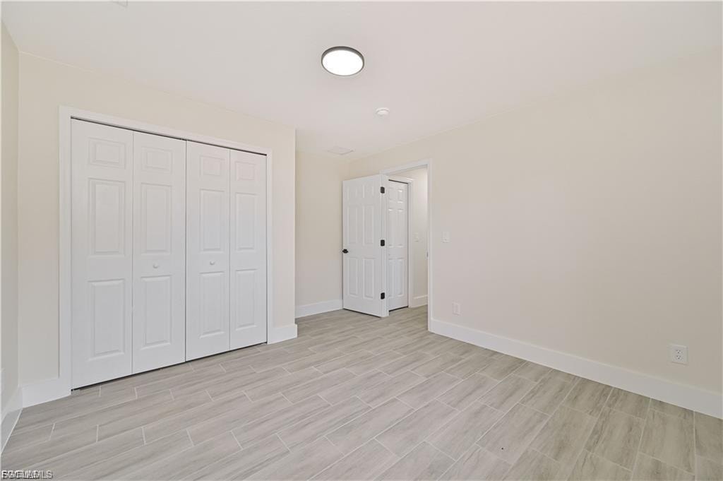 Spacious bedroom featuring luxury wood-finish flooring, dual closets with white six-panel doors, and recessed ceiling lighting