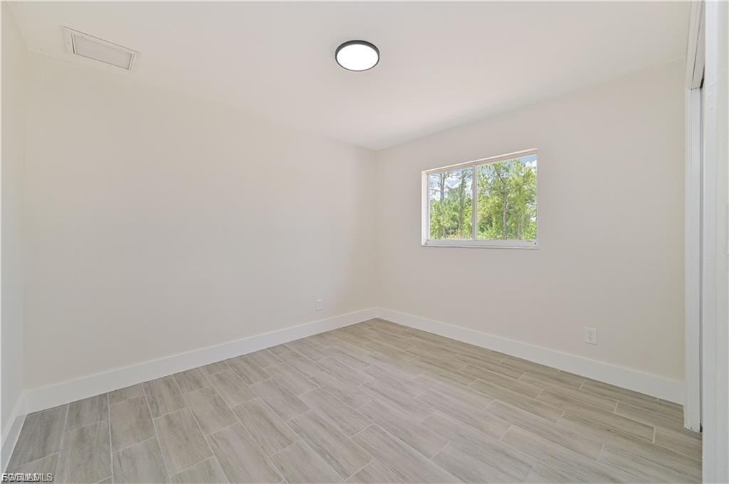 Recessed lighting, light gray wood-finish flooring, white walls, and a window